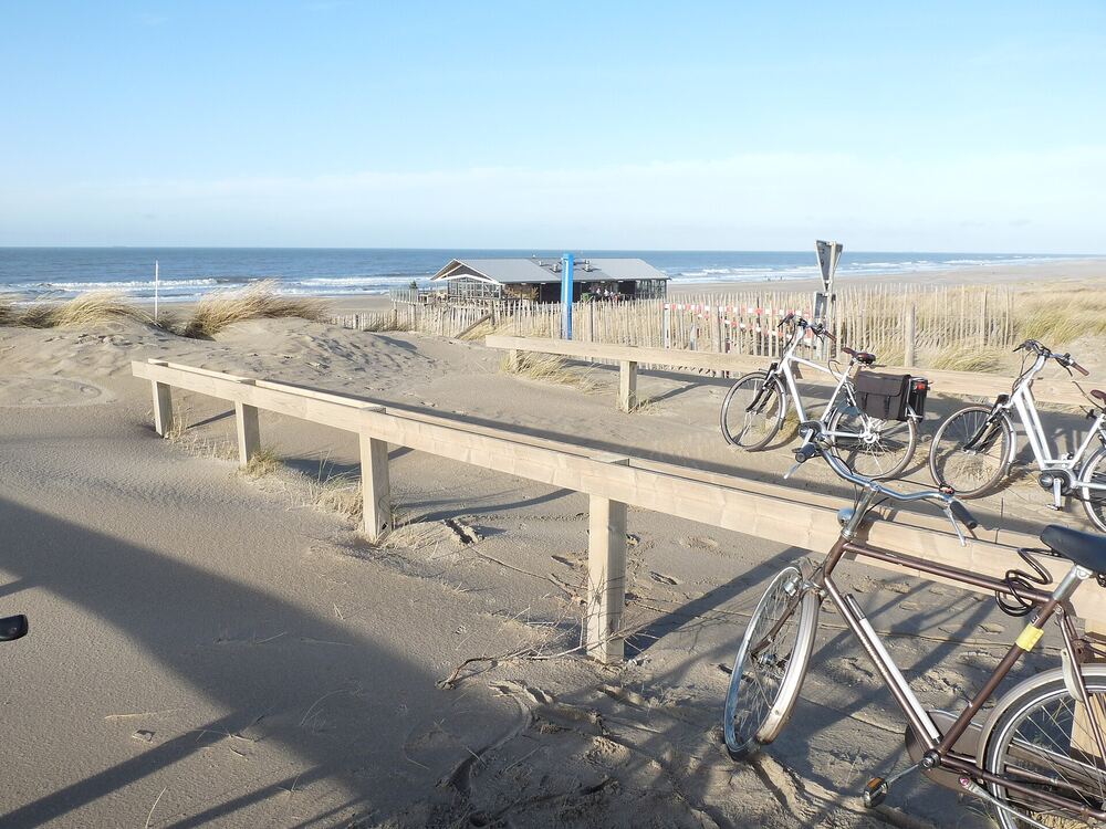Fietsen langs het duinpad bij de Zandmotor, met de zee op de achtergrond